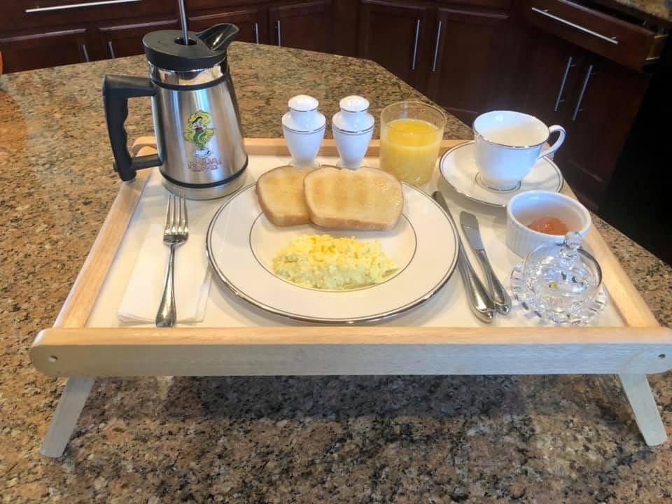 Breakfast of scrambled eggs, toast, coffee, and orange juice, served on china and crystal, arranged on a tray
