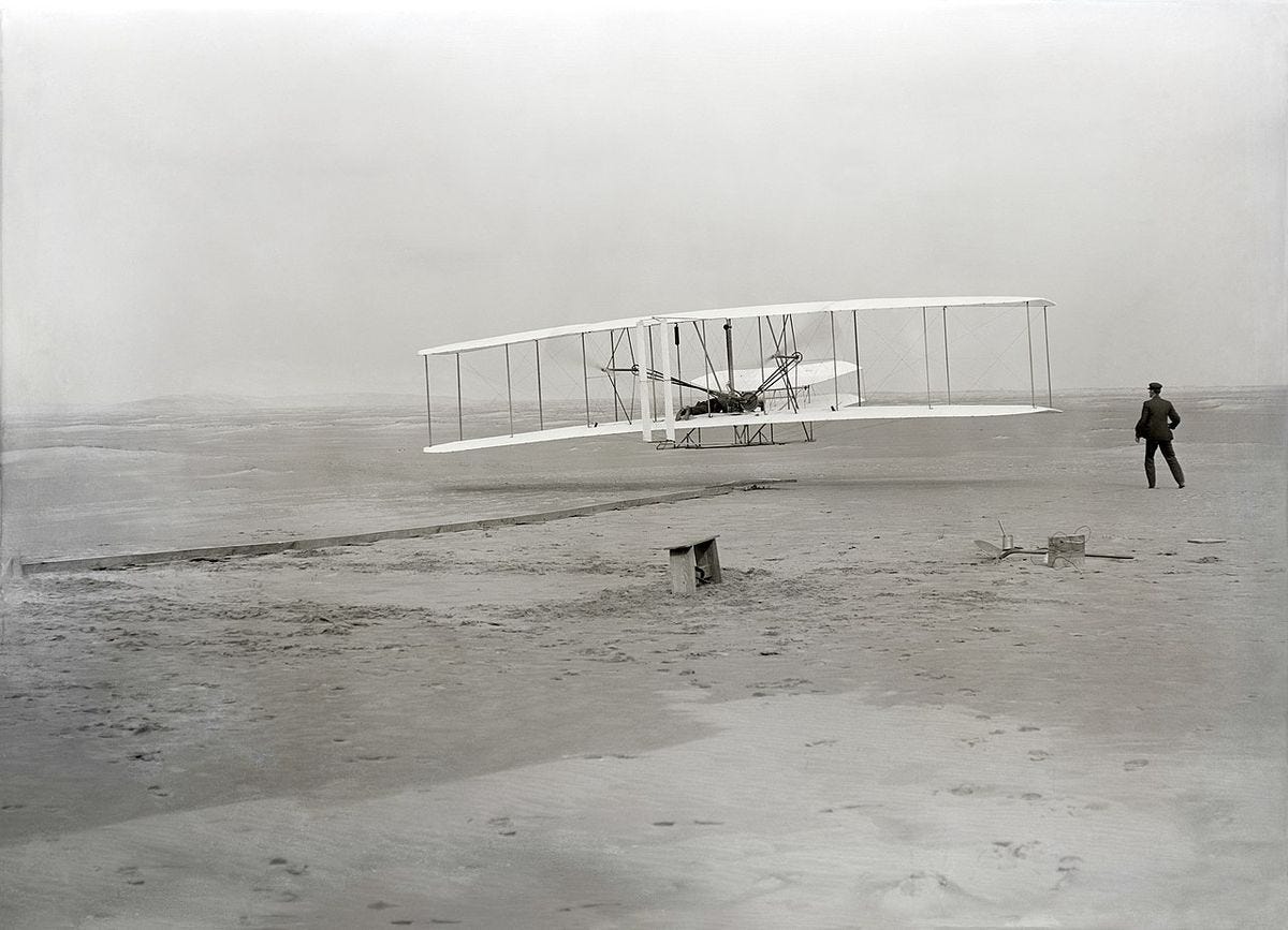 Seconds into the first ever flight of the Wright Flyer at Kitty Hawk, North Carolina. Orville Wright is flying, Wilbur Wright is running alongside.