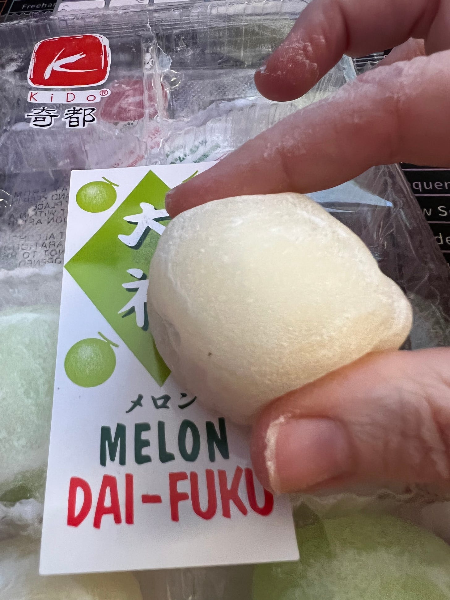 My fingers holding a small mochi ball, hovering over a plastic packet of melon and plain balls.Mochi is a Japanese rice cake made of mochigome, a short-grain japonica glutinous rice, and sometimes other ingredients such as water, sugar, and cornstarch. The rice is pounded into paste and molded into the desired shape. In Japan it is traditionally made in a ceremony called mochitsuki.