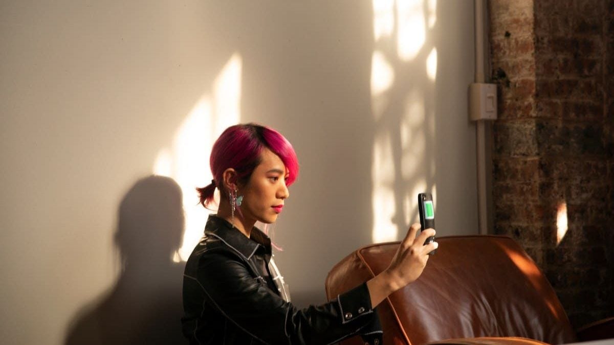 Una persona con i capelli rosa che si scatta un selfie con il telefono