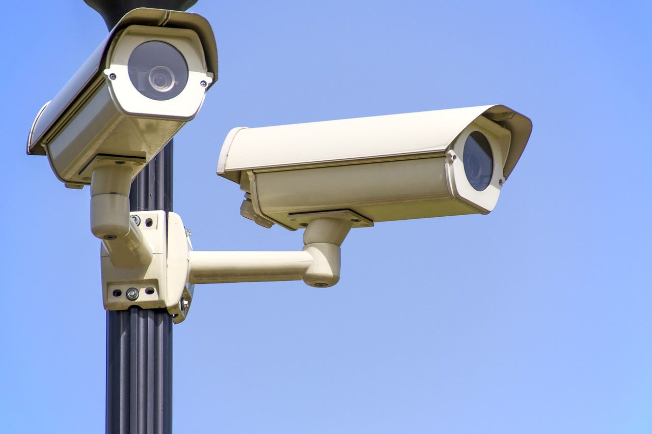 Surveillance cameras on a poll against a cloud-less sky