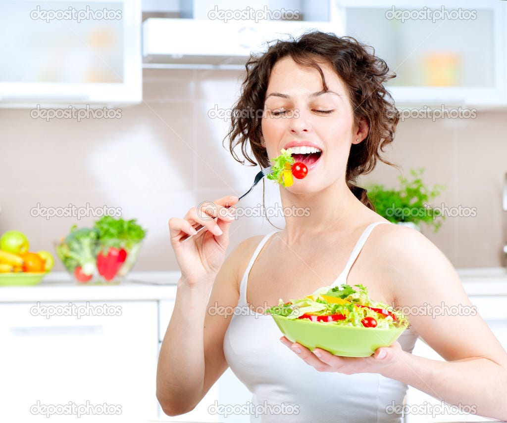 A stock photo from depositphotos of a white woman eating a salad while smiling