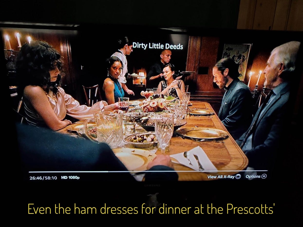 The family eats dinner at a table laden with fancy food, including for some reason a ham with pineapple and cherries, captioned "Even the ham dresses for dinner at the Prescotts'"