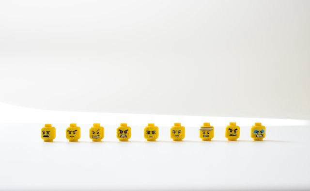 Lego figureine heads with different facial expressions in a line