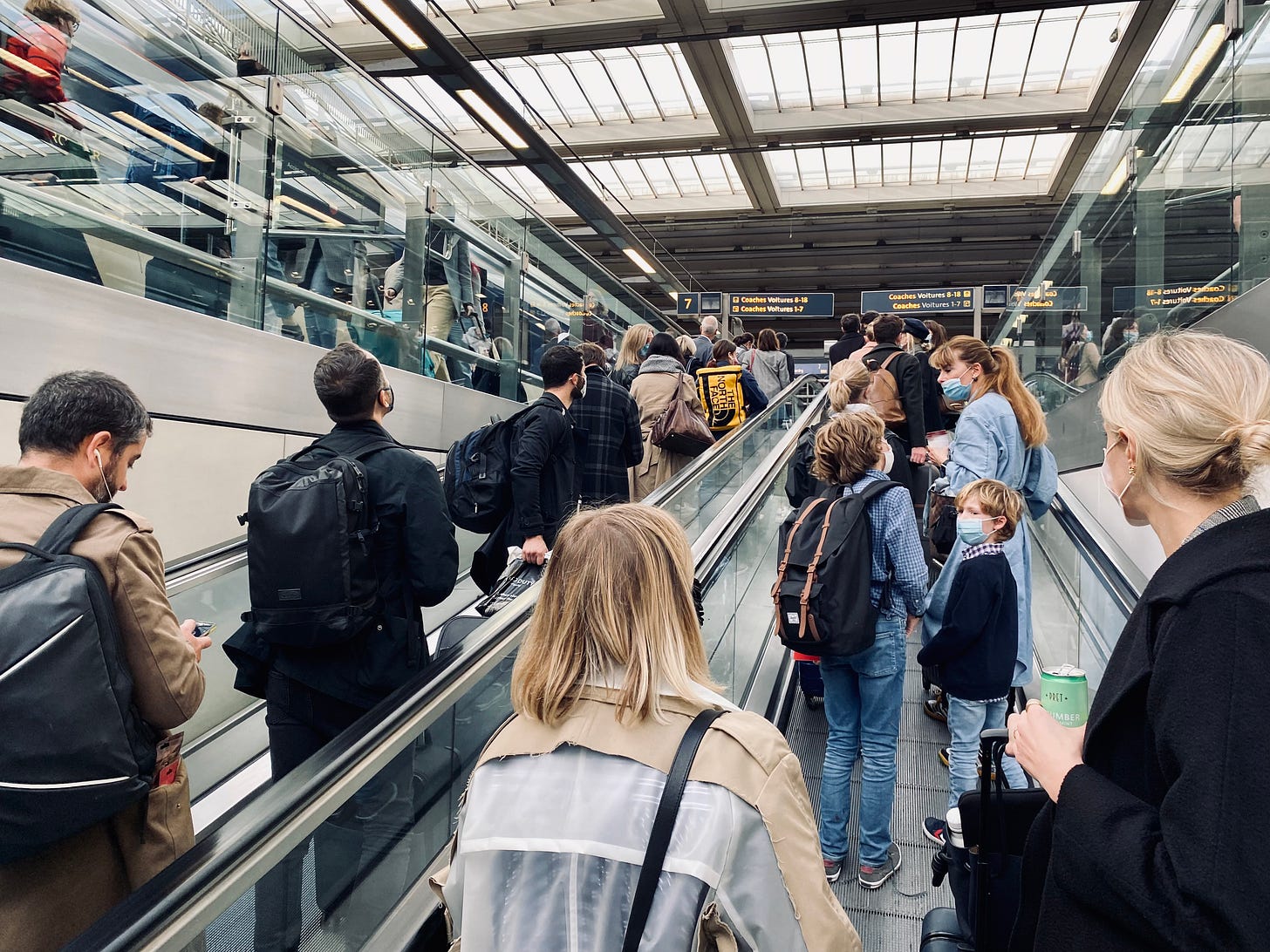 Passengers ascend a travelator on the way to a waiting Eurostar. Everyone is masked. Some of them properly.