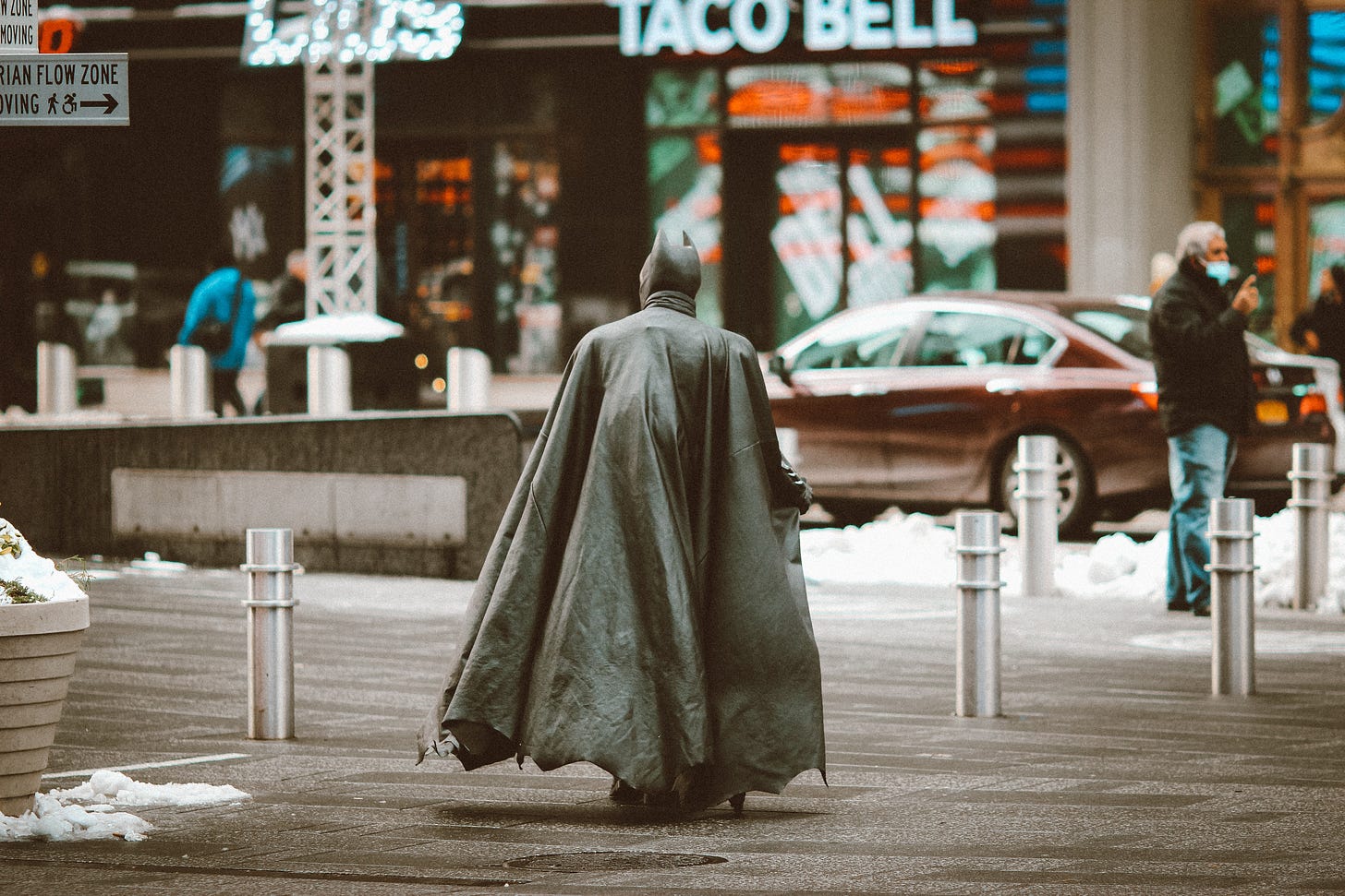 person in gray robe sitting on sidewalk during daytime photo