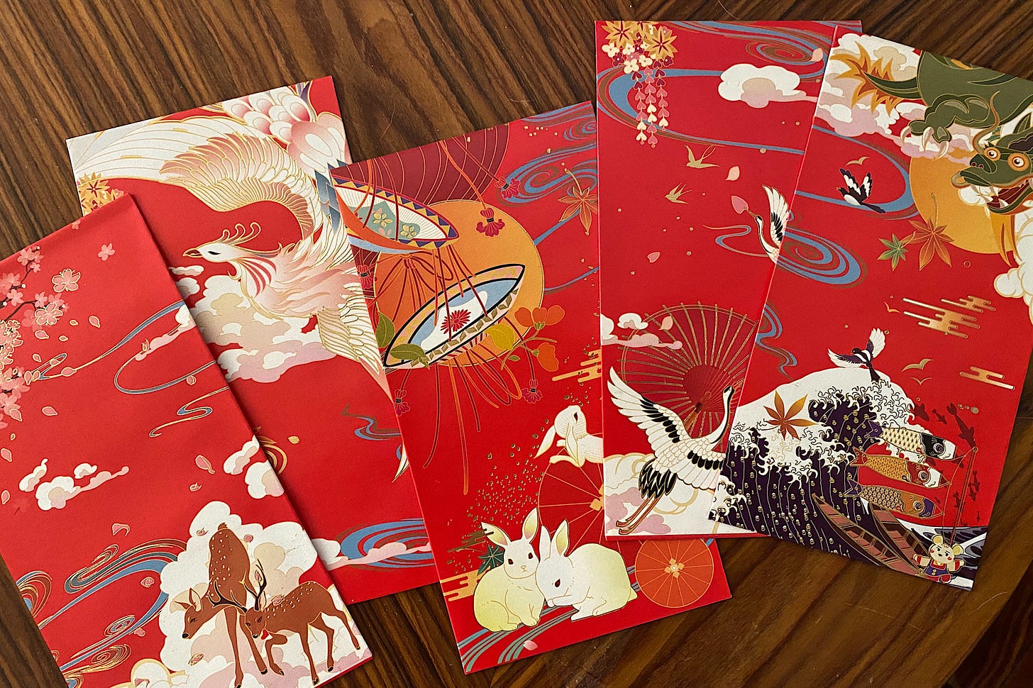 Image of five red envelopes festooned with deer, phoenix, rabbits, cranes, and dragons