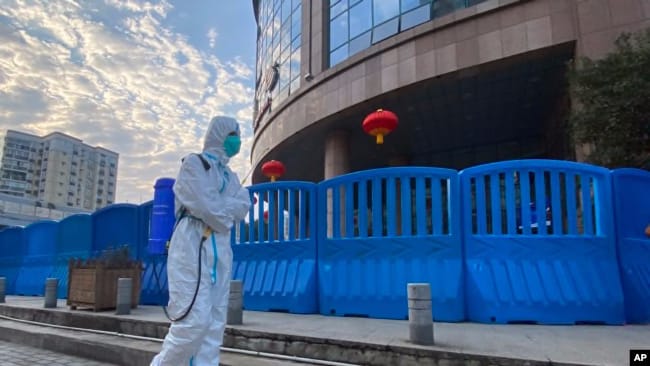 A worker in protective clothing and carrying disinfecting equipment walks outside the Wuhan Central Hospital in Wuhan, China on Feb. 6, 2021. 