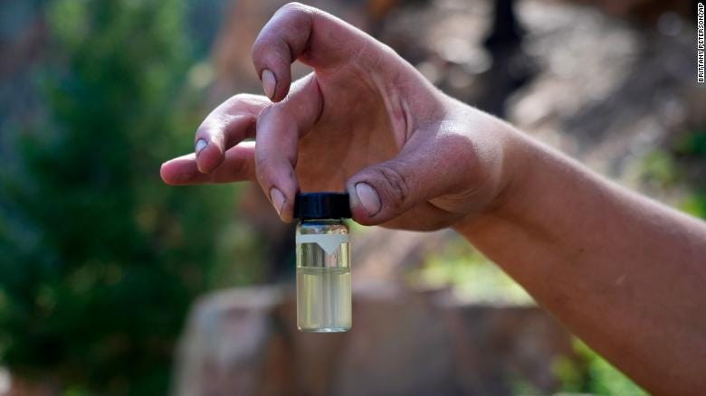A water treatment plant employee holds up a contaminated water sample from the Gallinas River in early August.