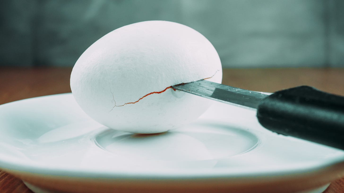 Kitchen knife cutting into an egg on a saucer