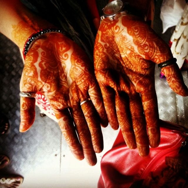 A pair of hands with dark mehendi on them.