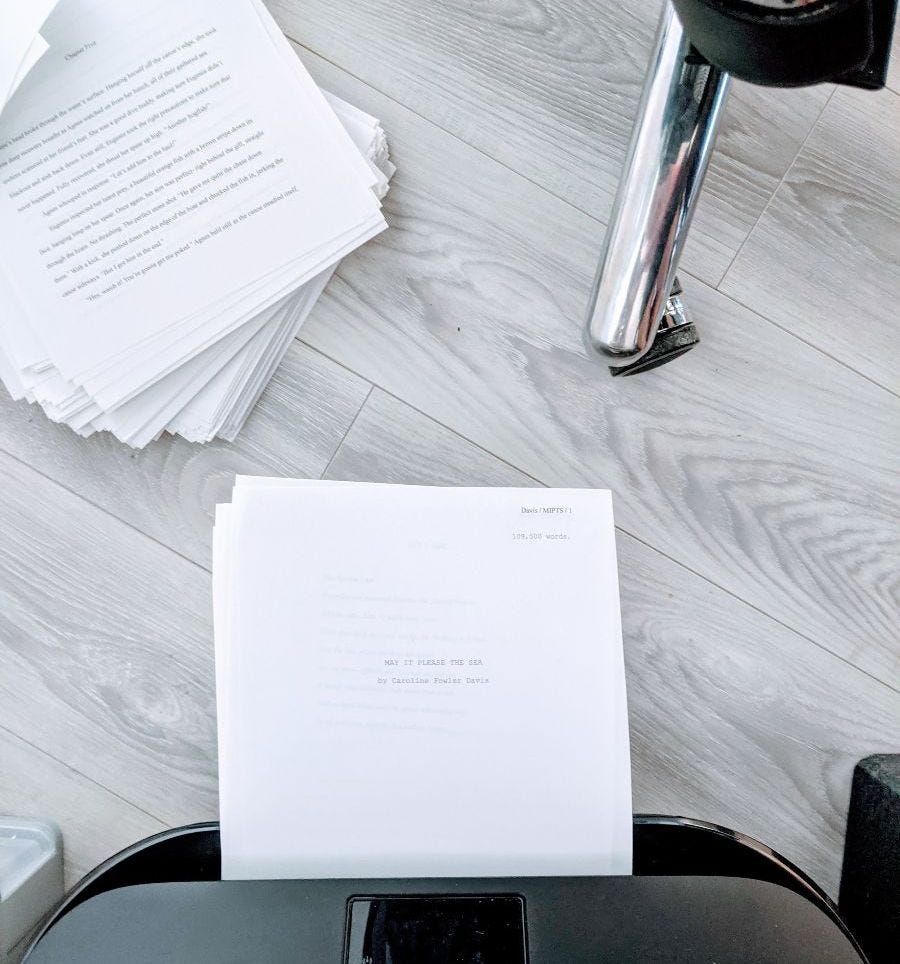 a manuscript resting on a printer on the office floor, pages scattered