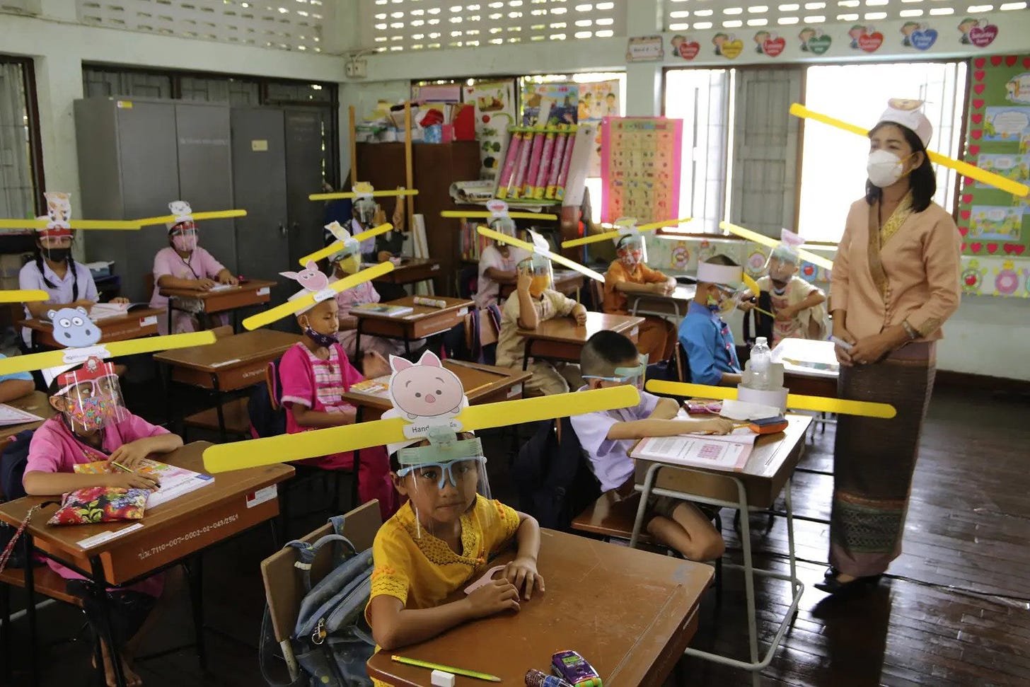 A teacher and students wear hats designed to practice social distancing to help curb the spread of the coronavirus at Ban Pa Muad School in Chiang Mai, north of Thailand, July 3.