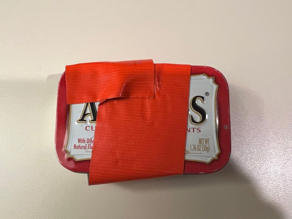 Altoid candy can wrapped with orange Gorilla duct tape for a fire making kit