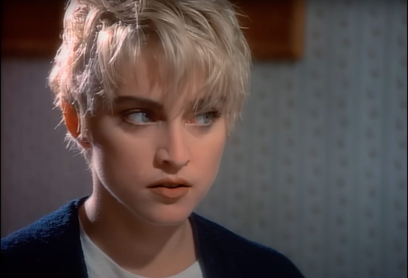 Madonna in the Papa Don't Preach video with a blond crop wearing a cardigan of all things