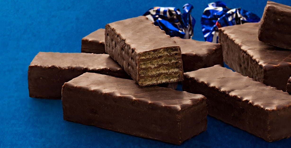 A picture of several chocolate-dipped wafers arranged on a blue surface with some wrapping papers on the background