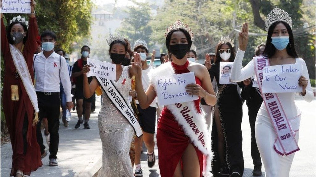 Participants of beauty pageants flash the three-finger salute and hold placards as they march in front of the US Embassy during a protest against the military coup, in Yangon, Myanmar, 10 February 2021