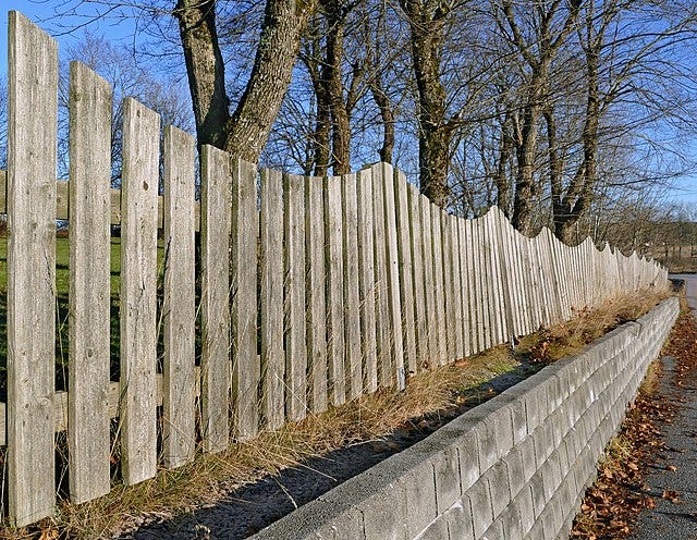 Photo of a wooden fence on a block retaining wall in Sweden, from Wikimedia Commons