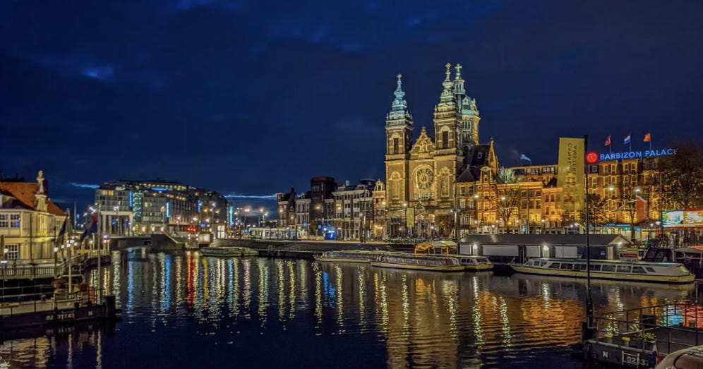 Amsterdam's waterfront at night, including the central train station, the rippled water reflecting the light. 