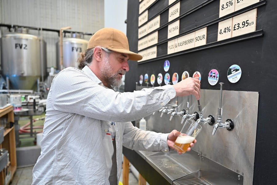 A worker pours a pint of beer at Pressure Drop Brewery, in north London, on May 21, 2022. Members of staff at the Pressure Drop brewery are taking part in a six-month trial of a four-day working week, with 3,000 others from 60 UK companies.