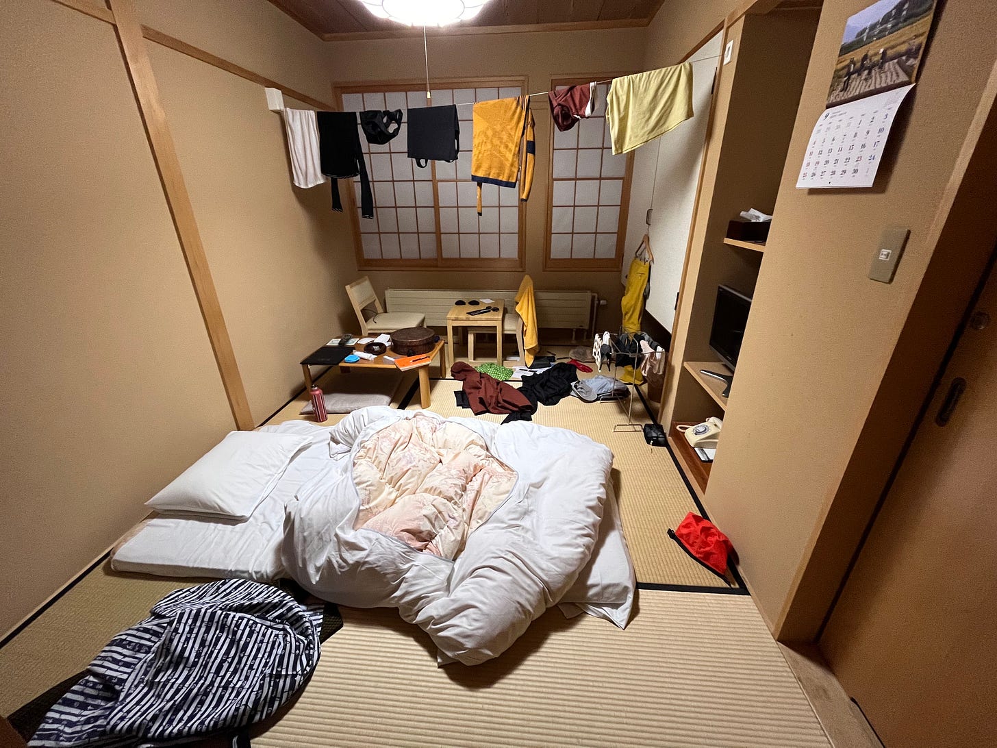 A tatami room with clothes hanging up to dry and objects scattered around the room.