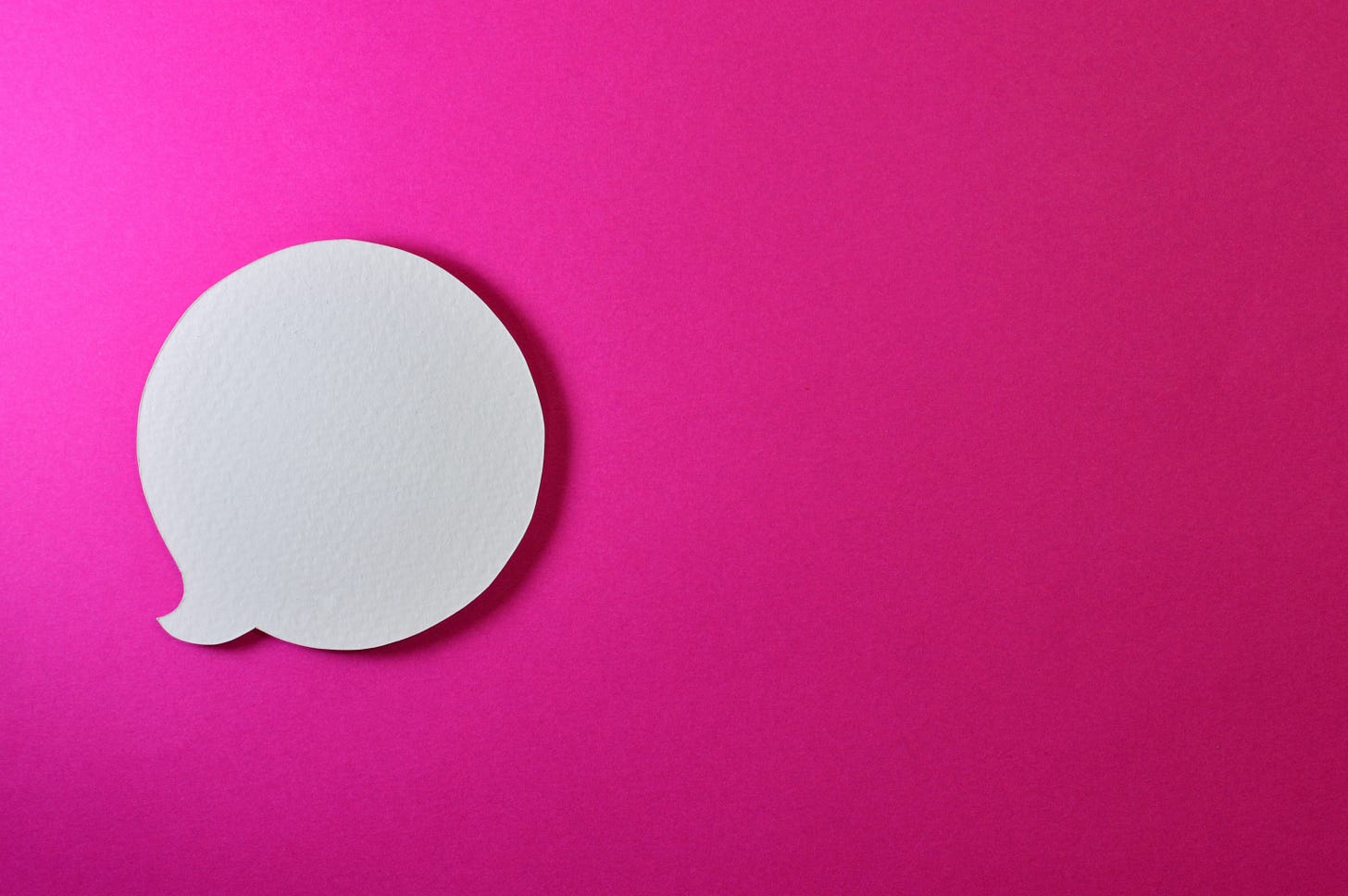 A white conversation bubble on a pink background.