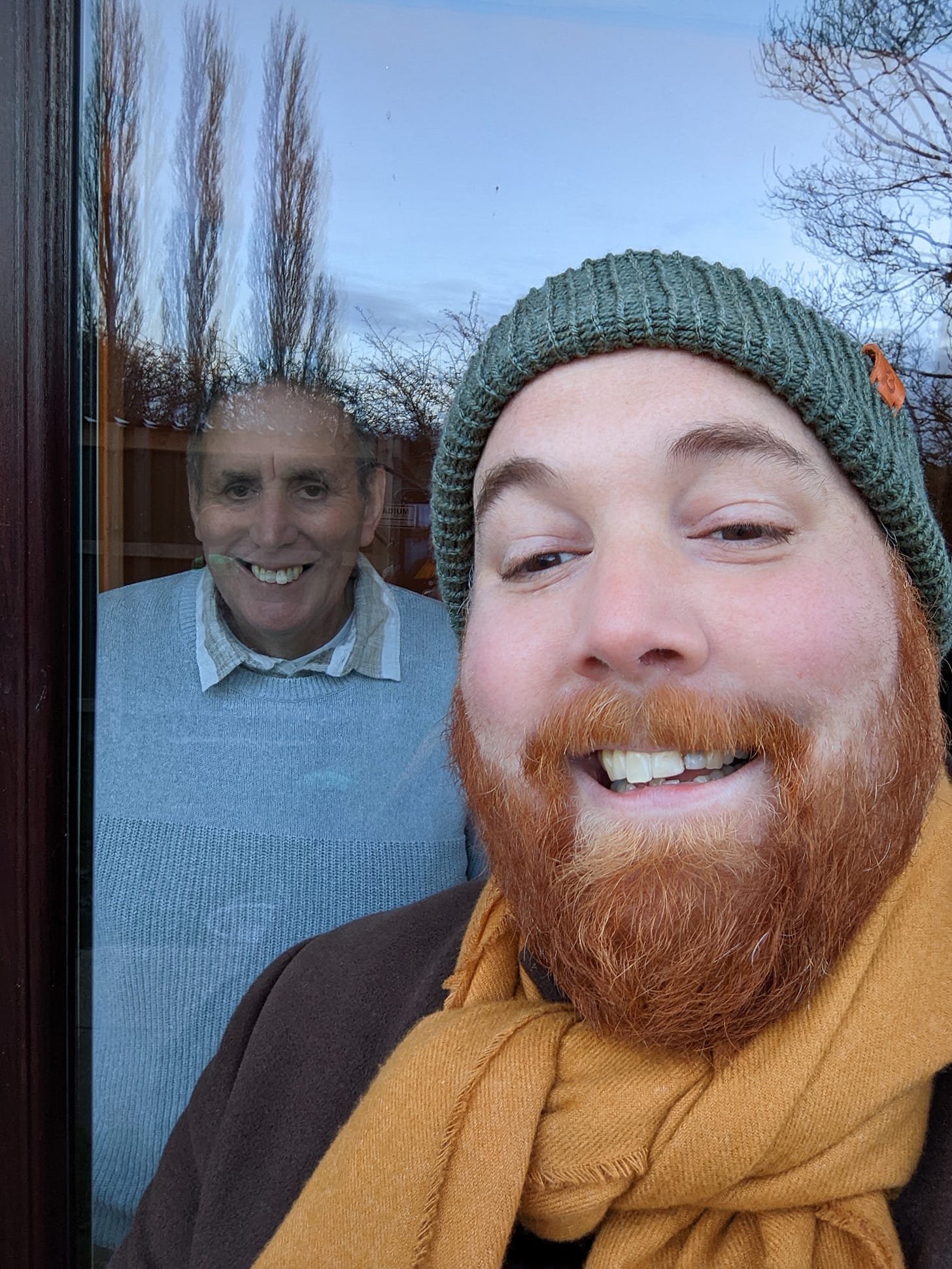 A selfie of my dad and I, with the window separating us during the restrictions in place due to COVID-19 in 2021. 