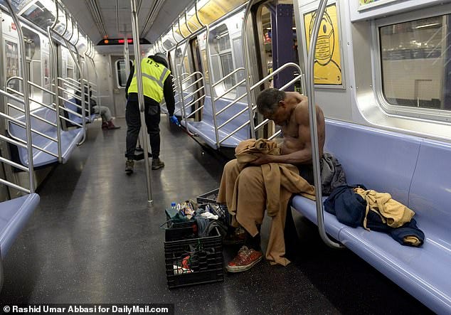 A shirtless, homeless man changes as he sits on the E train at the World Trade Center stop - the end of the line - while an MTA worker cleans the car. The Metropolitan Transportation Agency (MTA) said there are nearly 350 homeless people living in almost 90 subway stations and in 29 tunnels