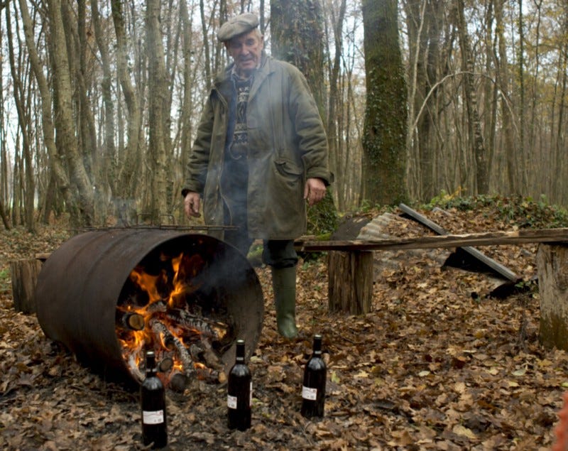A man tending to a bonfire in a barrel.