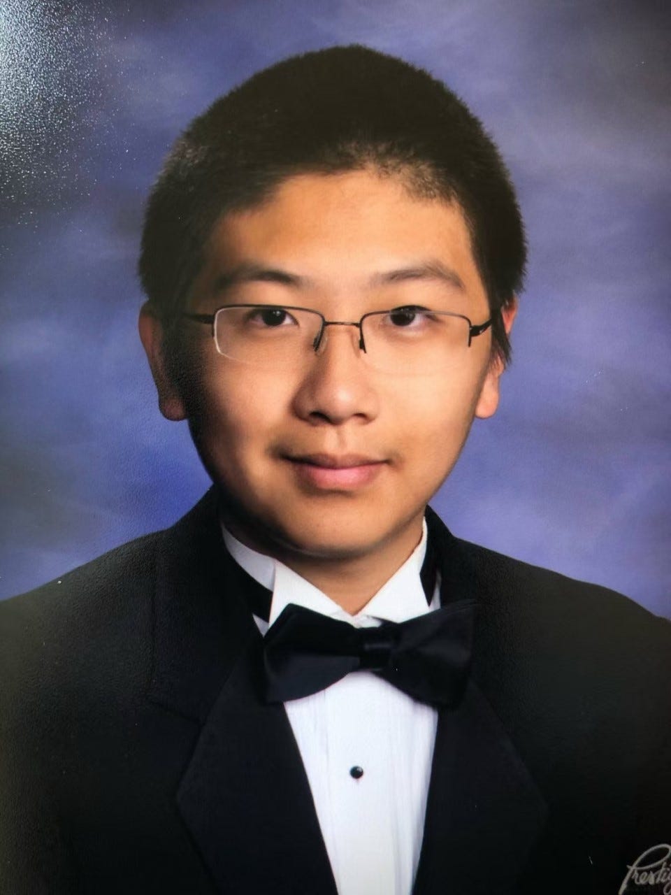 A photograph of Max as a high school senior wearing a tuxedo.