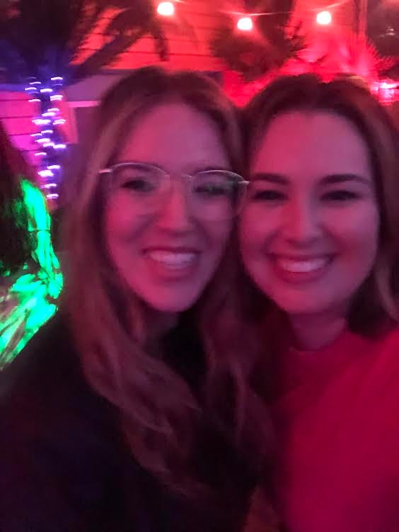 a blurry photo of two white women, one with short brunette hair and one with long blonde hair and glasses.