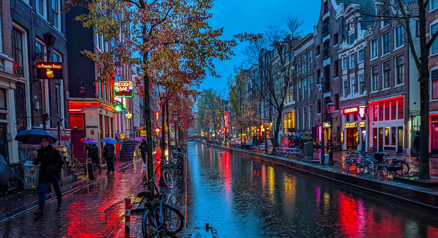 A canal at night in the Red Light District, with lots of red light reflected off of the water. 