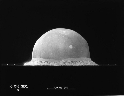 A black-and-white photograph of the upper hemisphere of a nuclear blast, with a timestamp and length scale