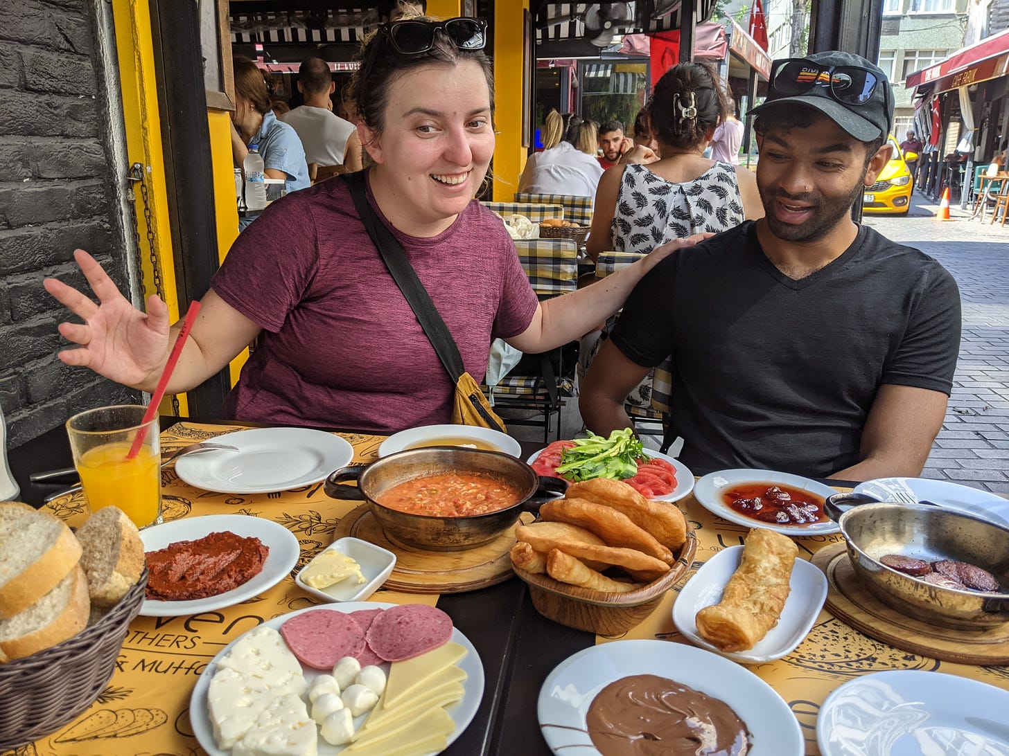 Aseef and Iulia are wowed before a table of many small plates, including 'menemen' -- Turkish scrambled eggs in a tomato sauce-- cheeses, meats, honey, clotted cream, and more. The table is laden and it looks like plates might well fall off by the time they're through.