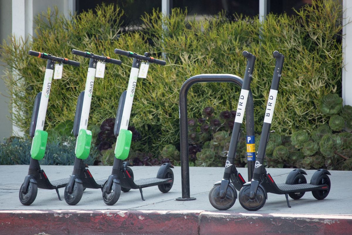 Electric scooters lined up on an LA sidewalk.