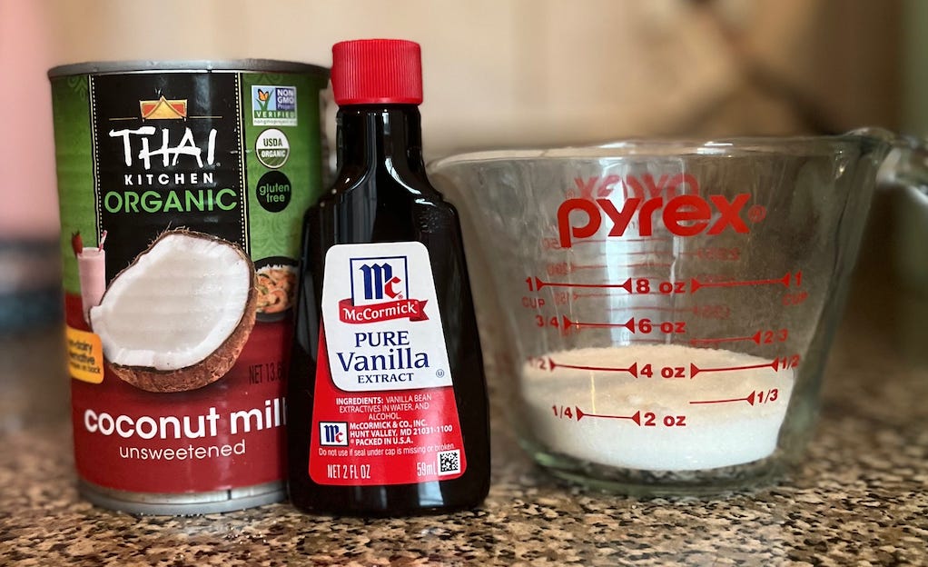 photo of coconut milk, vanilla extract, and measuring cup containing sugar and pinch of salt
