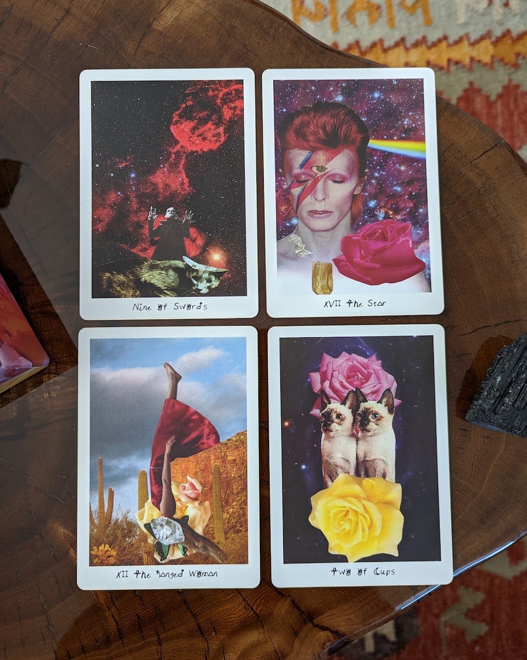 Four tarot cards from The Lioness Oracle tarot deck are spread out on a table: The Nine of Swords, The Star, The Hanged Woman, and the Two of Cups. The cards feature various collage artwork.