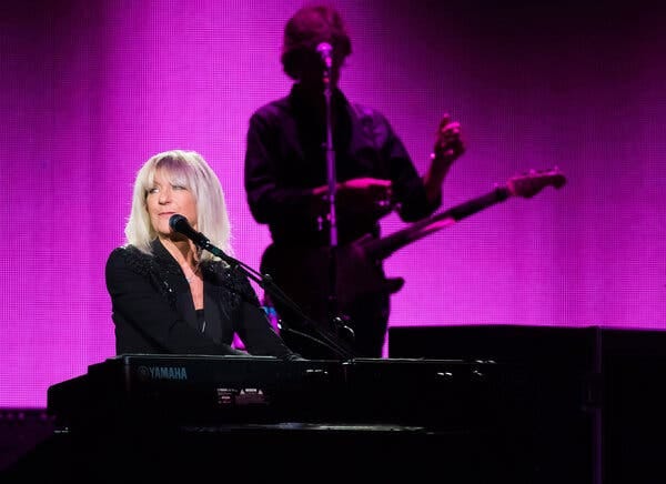 Christine McVie, seated at an electric keyboard and leaning into a vocal microphone (but not singing).