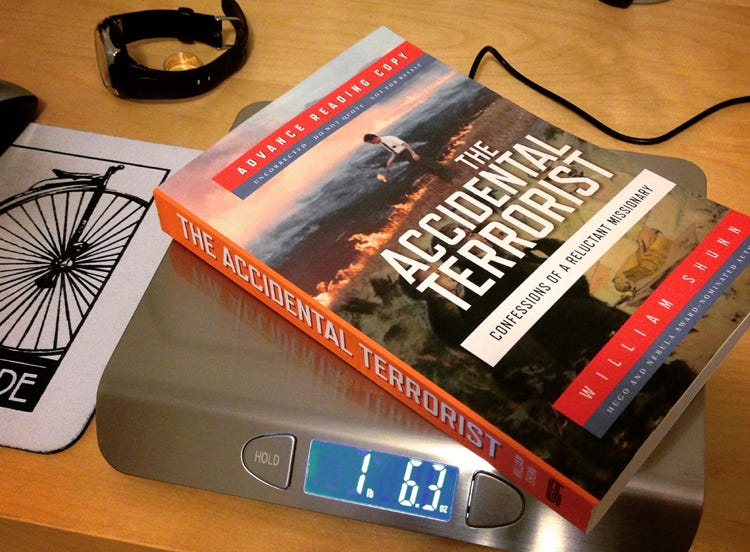 A trade paperback copy of The Accidental Terrorist, labeled "Advance Reading Copy," rests atop a digital scale which reads 1 pound 6.3 ounces.