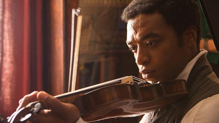 This image shows Solomon Northup (played by Chiwetel Ejiofor) playing the violin in Steve McQueen's 2013 film 12 Years a Slave.