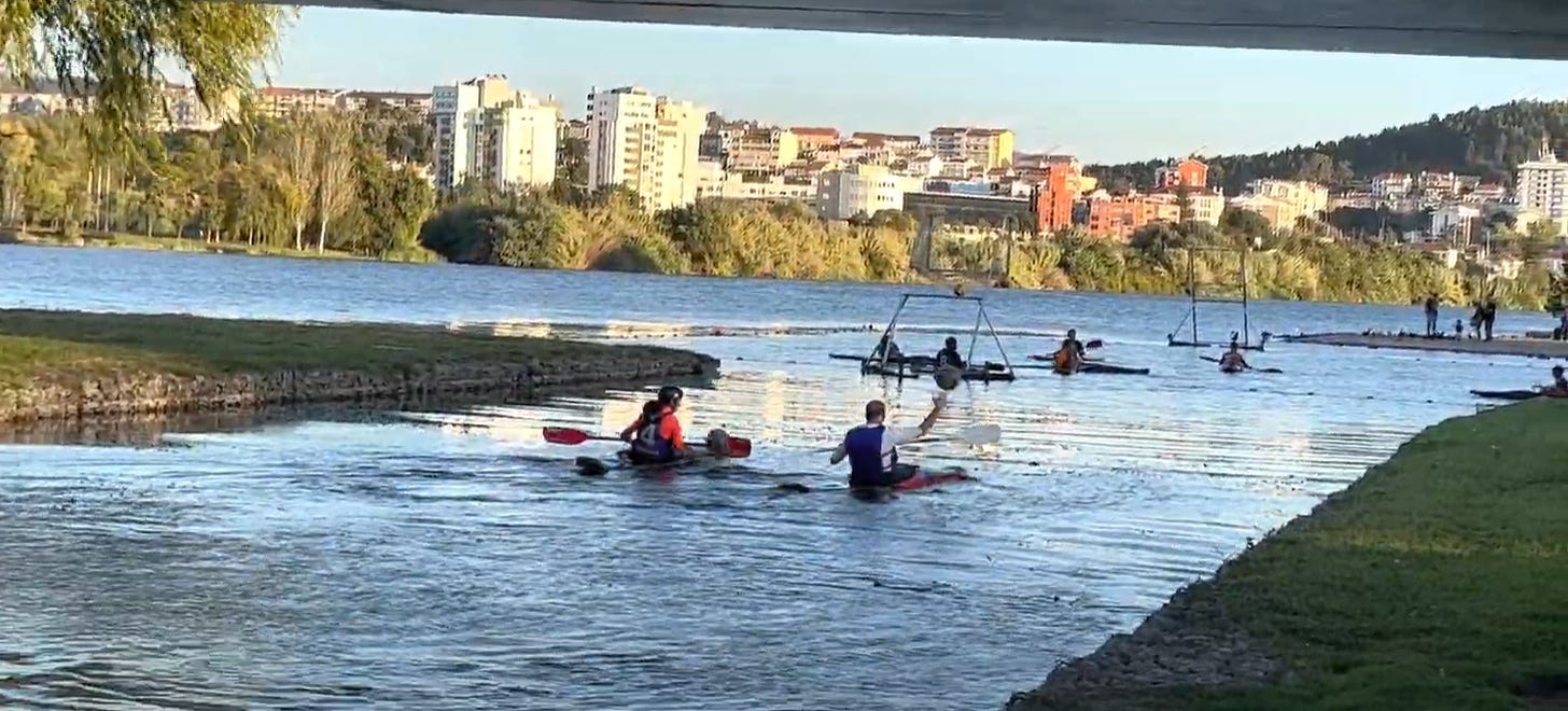 Kayakers paddle in the Mondego River, playing Kayak Polo