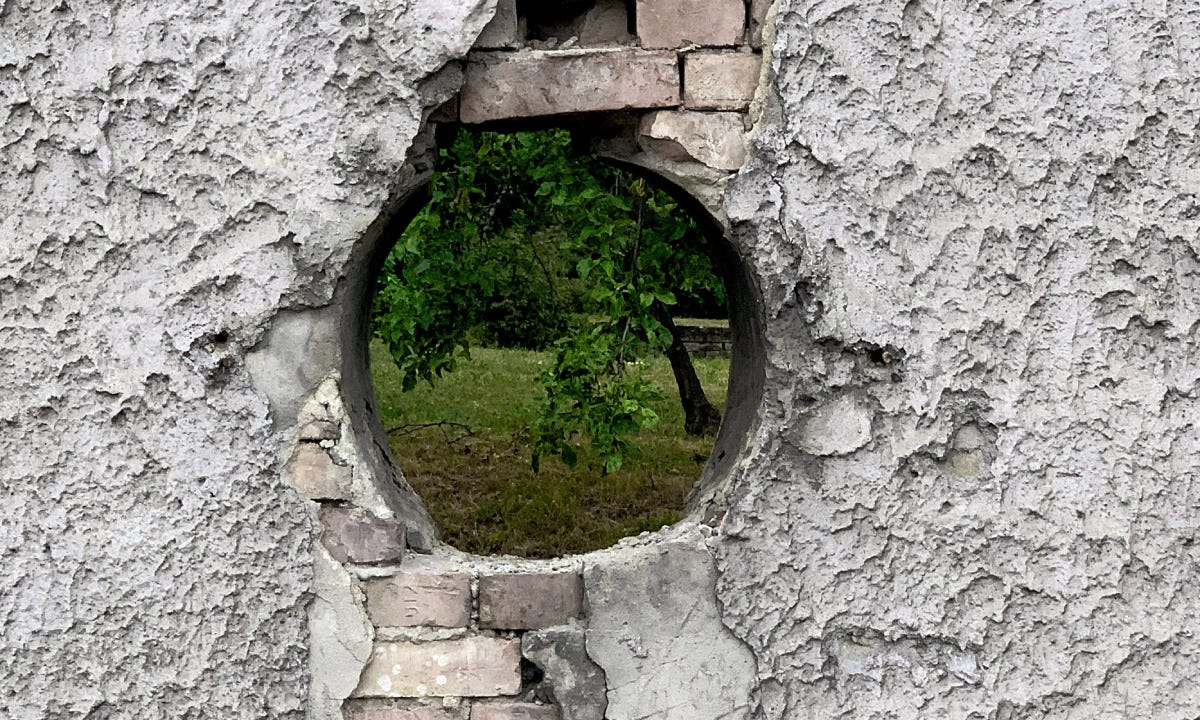 a hole in a wall, trees visible behind
