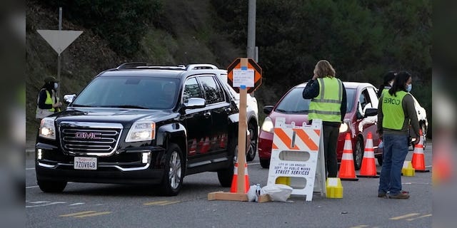 Drivers with a vaccine appointment enter a mega COVID-19 vaccination site set up in the parking lot of Dodger Stadium in Los Angeles Saturday, Jan. 30, 2021. One of the largest vaccination sites in the country was temporarily shut down Saturday because dozen of protesters blocked the entrance, stalling hundreds of motorists who had been waiting in line for hours, the Los Angeles Times reported. The Los Angeles Fire Department shut the entrance to the vaccination center at Dodger Stadium about 2 p.m. as a precaution, officials told the newspaper. The protesters had members of anti-vaccine and far-right groups, the Times reported. Some of them carried signs decrying the COVID-19 vaccine and shouting for people not to get the shots. (AP Photo/Damian Dovarganes)