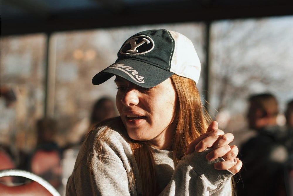 woman wearing grey sweater and cap looking side