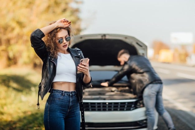 Portrait of beautiful young woman using her mobile phone calls for assistance for car. Free Photo