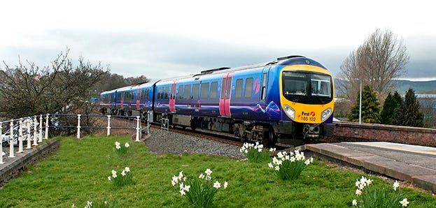 A Transpennine Express Train operating on the Windemere branch line. There are flowers in the foreground