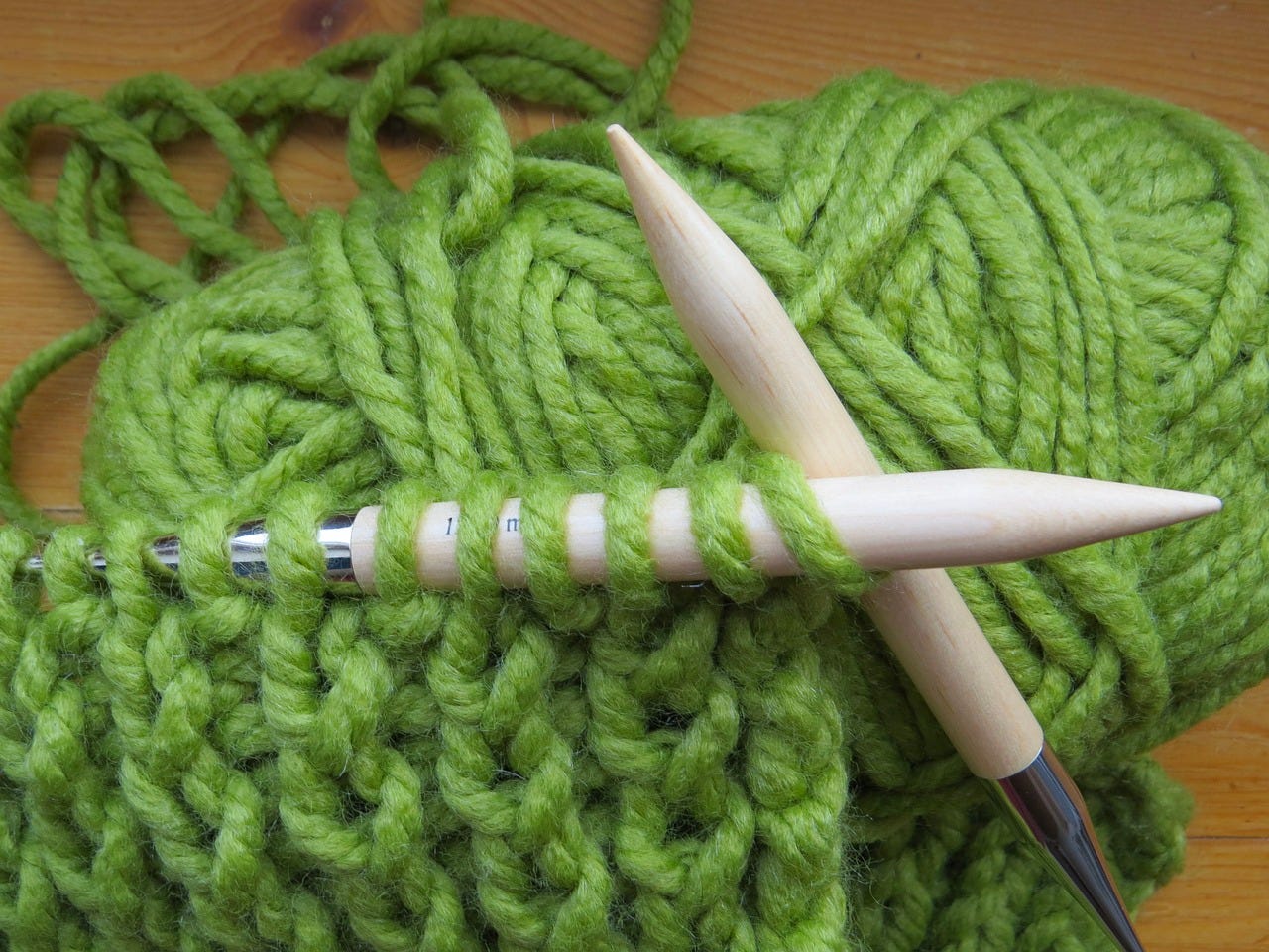 green yarn skein, needles, and knitting