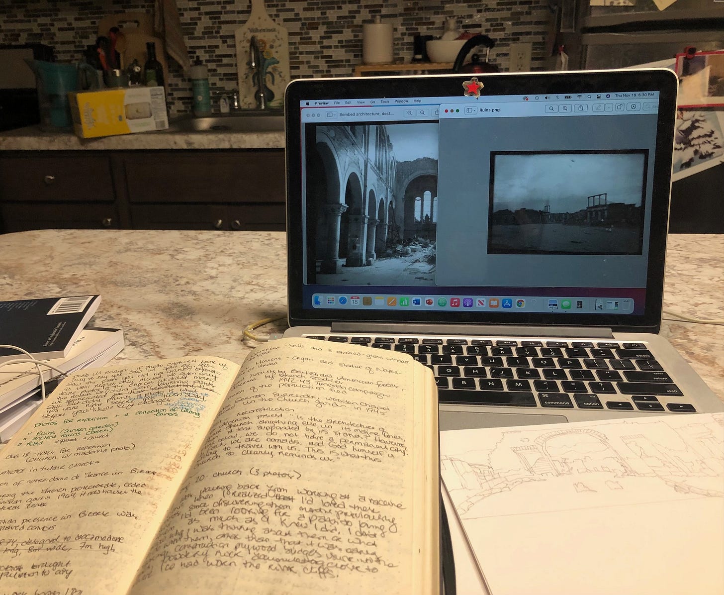 A laptop showing two archival photos of Bizerte, Tunisia, from the 1940s and an open notebook with messy notes