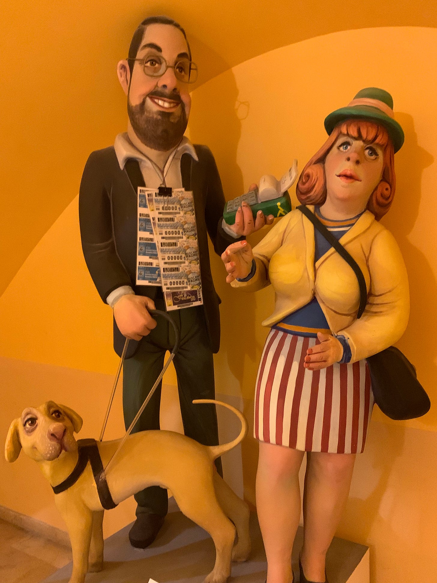 A ninot depicting a man and a woman, both ONCE employees. The man has a guide dog and raffle tickets.