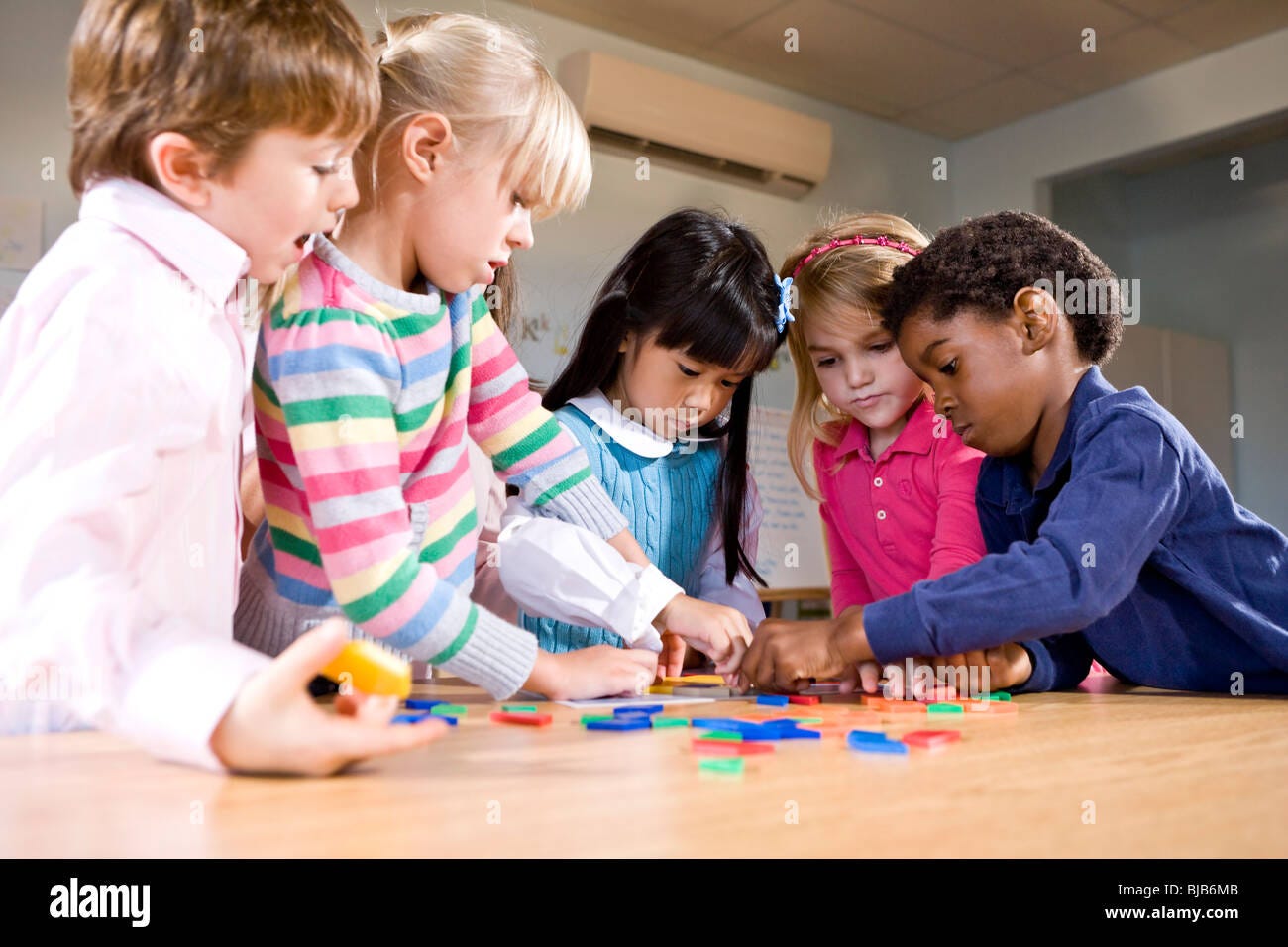 Preschool children working together on puzzle Stock Photo - Alamy